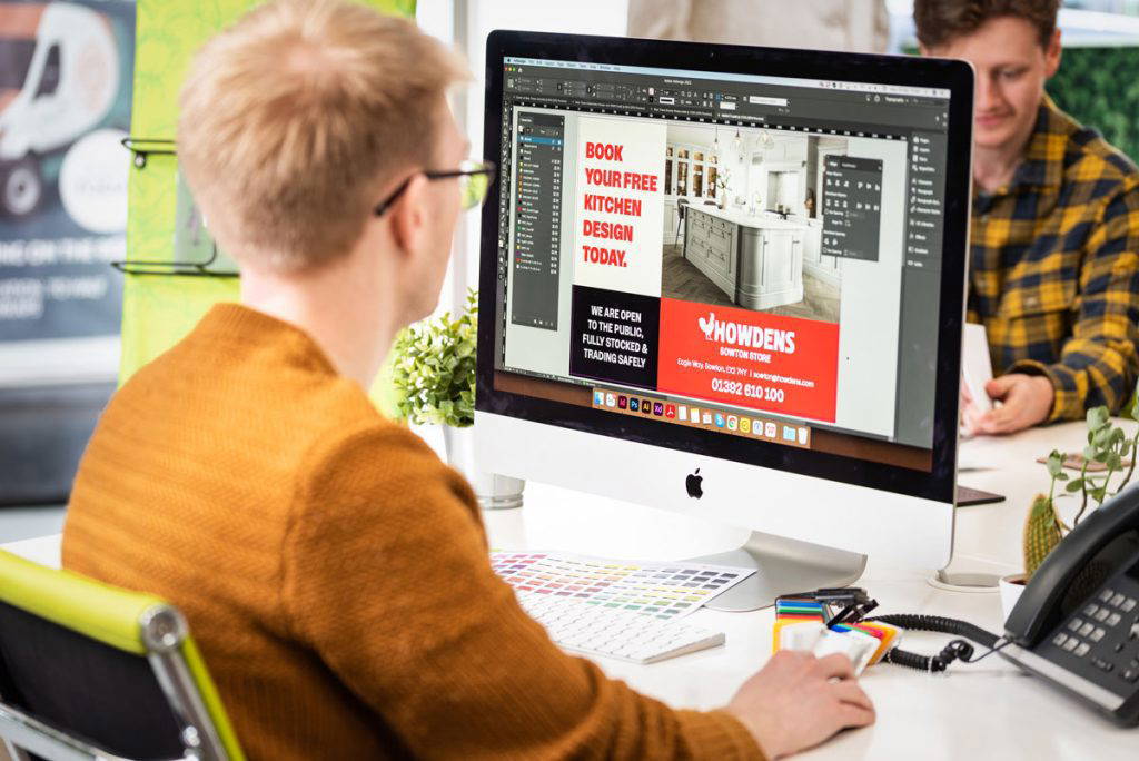 print design expert sits at apple computer designing a flyer for a local business