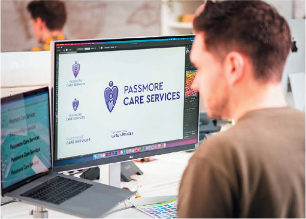 graphic designer sat at computer working with design software to create a logo and brand identity for local stockport care service business.